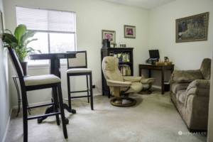 An office with chairs, couch, desk, bookcase, art on the wall