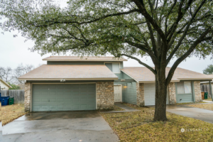 Street view of a home with attached garage and a tree in the front yard